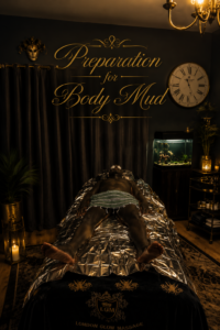 Dimly lit spa room with a man lying on a shiny, metallic-covered bed for a body mud treatment, behind a wall reading 'Preparation for Body Mud'.